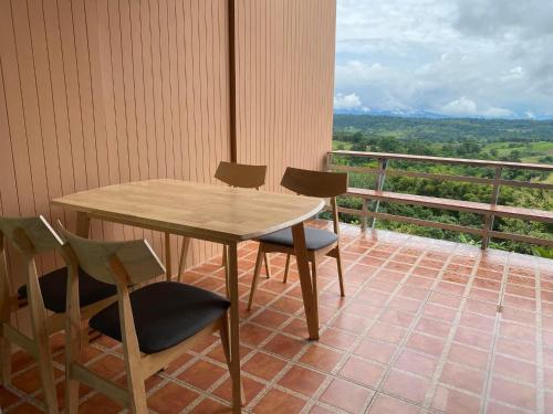 a table and chairs on a balcony with a view at บ้านภูไผ่ ไร่ภูไผ่เบิกตะวัน in Ban Nam Phang