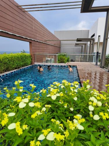 Tres personas en una piscina con flores amarillas en Woodsbury Suites IKEA House Butterworth Penang en Butterworth