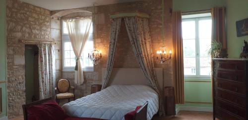 een slaapkamer met een hemelbed en een raam bij Chambre Louis XVI au Château de Champagne-Mouton in Champagne-Mouton