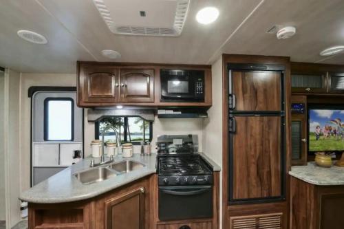 an rv kitchen with a sink and a stove at Heartland North Trail 31' RV in Manchaca