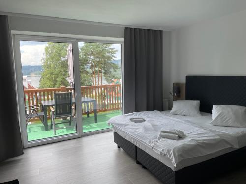 1 Schlafzimmer mit einem Bett und einem Balkon mit einem Tisch in der Unterkunft Apartmán Kapy Lipno in Lipno nad Vltavou