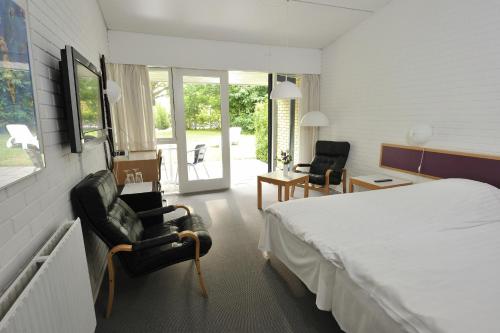 a hotel room with a bed and two chairs at Hotel Balka Strand in Neksø