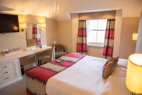 a hotel room with a bed and a desk at Best Western York House Hotel in Eastbourne