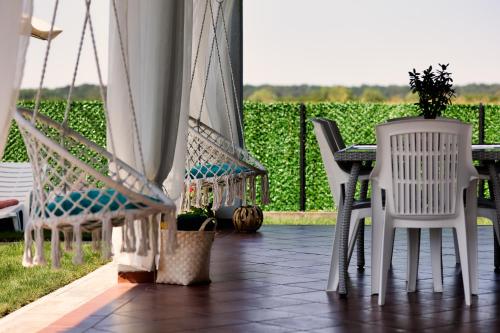 a porch with white chairs and a table with a view of a vineyard at Green Art House in Kovilovo