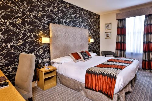 a hotel room with a bed and a desk at Best Western York House Hotel in Eastbourne