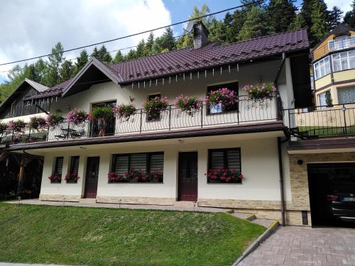 une maison blanche avec des boîtes de fleurs sur les balcons dans l'établissement u Gosi, à Krynica-Zdrój