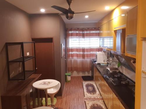 a small kitchen with a table and a ceiling fan at Mountain View Homestay in Seremban