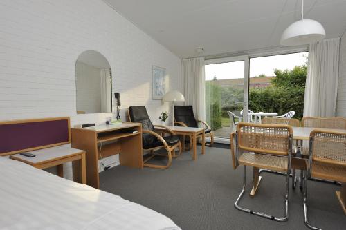 a room with a bed and a desk and chairs at Hotel Balka Strand in Neksø