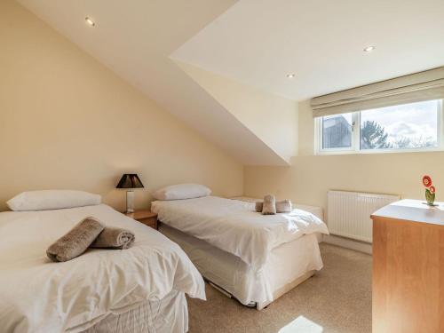two beds in a room with a window at Brick Kiln Cottage in Burton Overy