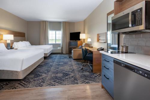ein Hotelzimmer mit 2 Betten, einem Schreibtisch und einer Küche in der Unterkunft Candlewood Suites Grand Junction, an IHG Hotel in Grand Junction