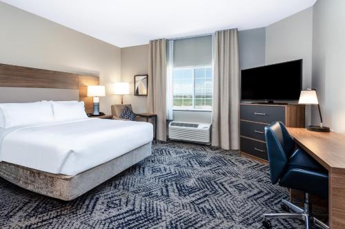 a hotel room with a bed and a desk and a television at Candlewood Suites Grand Junction by IHG in Grand Junction