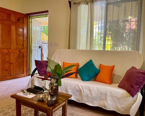 a living room with a couch with colorful pillows on it at The Inner Light Yoga Lodge in Sámara