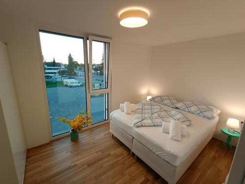 1 dormitorio con cama y ventana grande en Neu erstellte Wohnung mit Balkon in Hard, en Hard