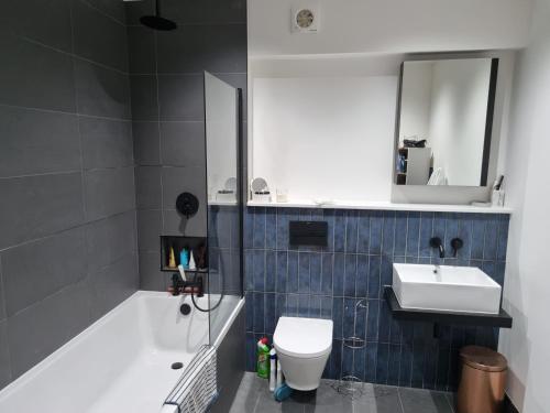 a bathroom with a tub and a toilet and a sink at Bright spacious apartment in the park in London