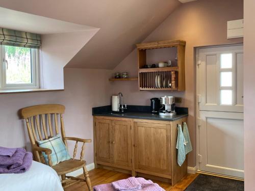 a kitchen with a counter and a chair in a room at The Hayloft, Exmoor in Withypool