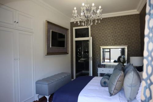a bedroom with a bed and a chandelier at Villa Grande Luxury accommodation in Welkom