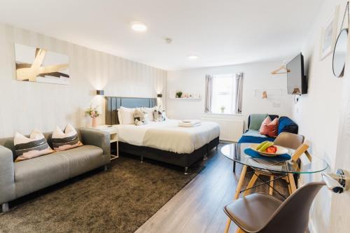ein Hotelzimmer mit einem Bett, einem Sofa und einem Tisch in der Unterkunft Prime Suites Lytham in Lytham St Annes