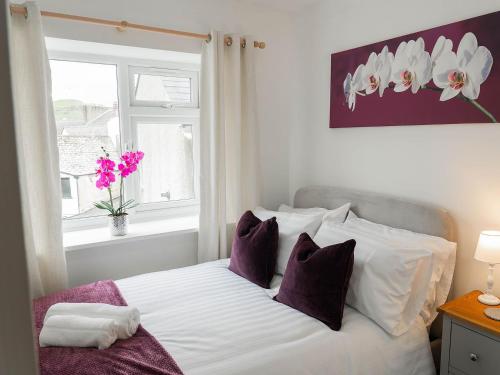 a bedroom with a bed with purple and white pillows at White Hart Cottage in Ulverston