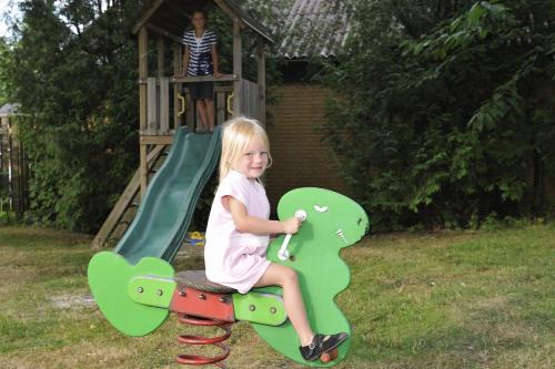 a little girl sitting on a slide in a playground at Hotel Balka Strand in Neksø