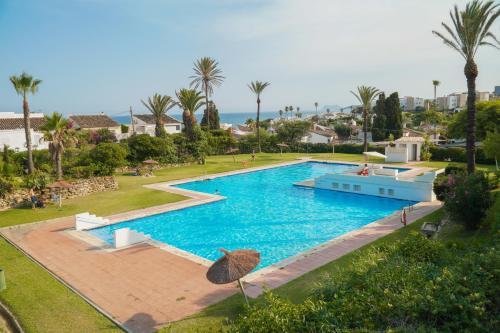 einen Blick über einen Pool mit Palmen in der Unterkunft Beach Villa Dorada in Estepona