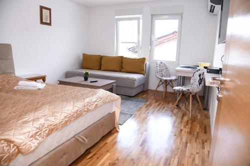 een kleine slaapkamer met een bed en een bank bij Demir Apartmani in Novi Pazar