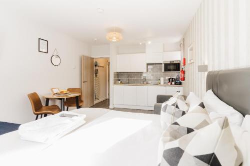 a bedroom with a large white bed and a kitchen at Prime Suites Lytham in Lytham St Annes