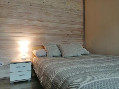 a bedroom with a bed with a wooden wall at Apartamenti Miera Osta in Liepāja