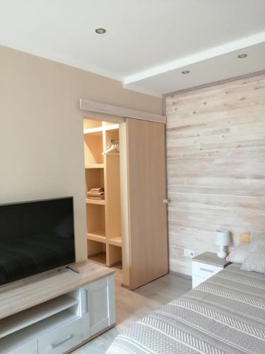 a bedroom with a flat screen tv and a wooden wall at Apartamenti Miera Osta in Liepāja