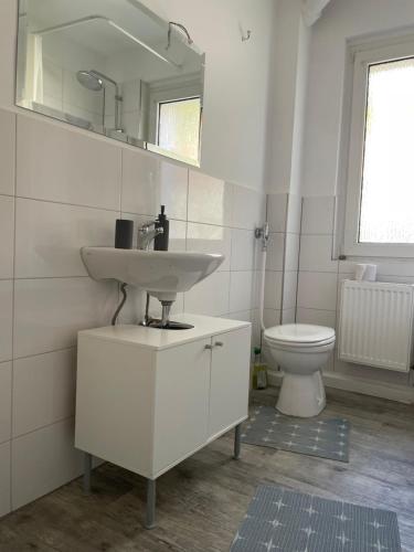 La salle de bains blanche est pourvue d'un lavabo et de toilettes. dans l'établissement estrella24 LIVING ROOMS London, à Herne