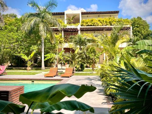 a resort with a swimming pool and palm trees at XscapeTulum in Tulum