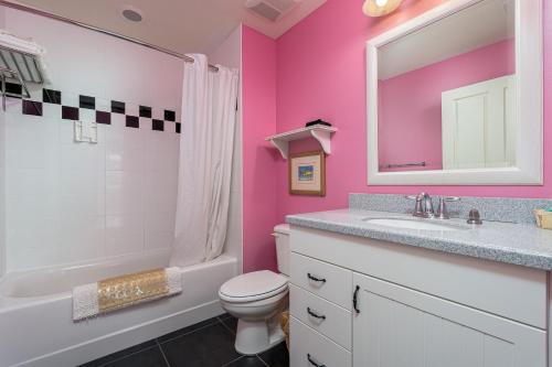 różowa łazienka z umywalką, toaletą i lustrem w obiekcie Harbour House at the Inn 214 w mieście Fort Myers Beach