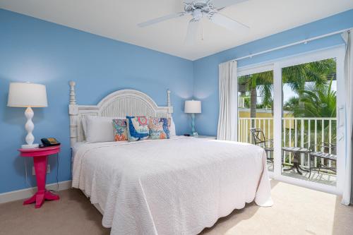 a blue bedroom with a bed and a balcony at Harbour House at the Inn 214 in Fort Myers Beach