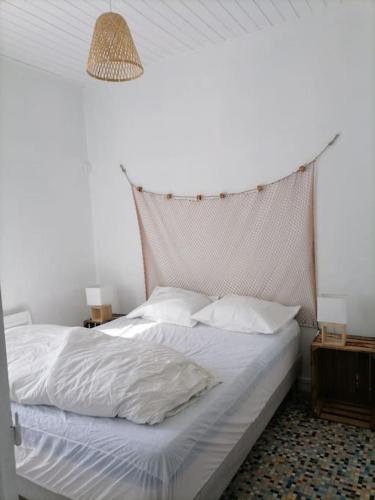 uma cama com lençóis brancos e almofadas num quarto em Maison de pecheur cour privée en centre ville em Saint-Gilles-Croix-de-Vie