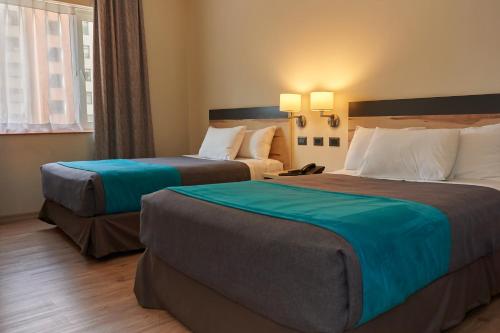 a hotel room with two beds and a window at Hotel Diego de Almagro Talca Express in Talca