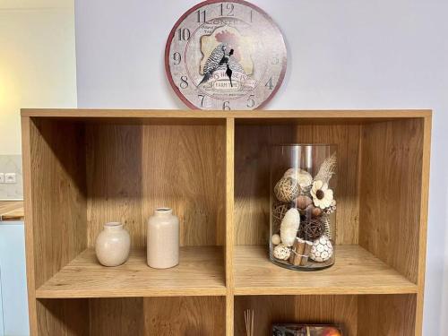 a wooden shelf with a clock and vases on it at Appartement • Paris/Disney • 1 Min Gare in Bussy-Saint-Georges