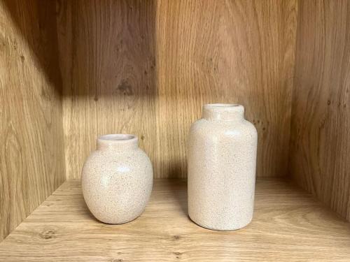 two white vases sitting on a wooden shelf at Appartement • Paris/Disney • 1 Min Gare in Bussy-Saint-Georges