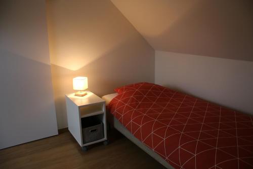 Bas CoronにあるCharmante maison de campagne "Chemin Saint-Roch"の小さなベッドルーム(赤いベッド1台、ランプ付)