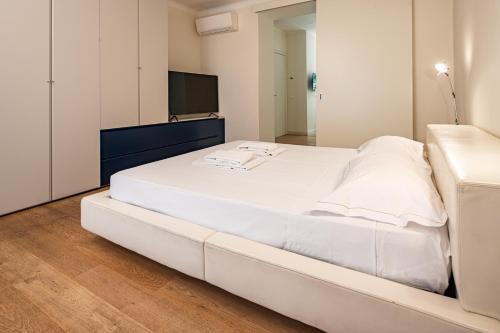 uma grande cama branca num quarto com televisão em Brera Livings, Charming flat near Duomo em Milão
