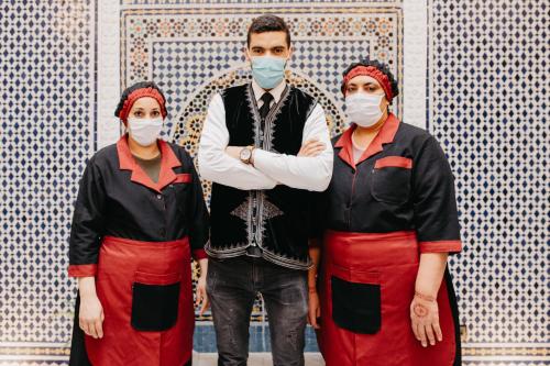 a man and two women wearing face masks in front of a wall at Riad Farah in Fez