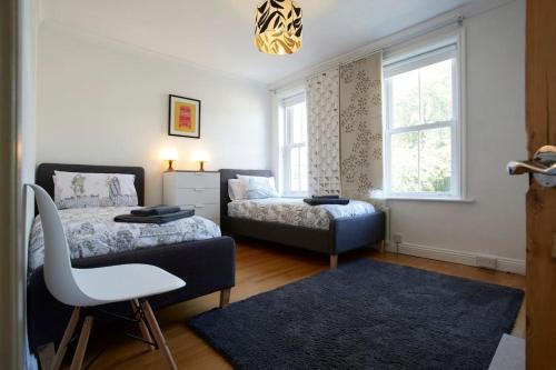 a bedroom with a bed and a chair and a window at Central Harrogate Townhouse - HIC Bottom of road! in Harrogate