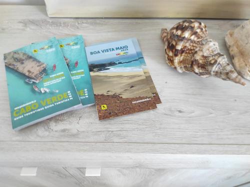 two books sitting on a table with a seashell at Beach house Agua Viva, Praia de Chaves, Boa Vista, Sal Rei, Cape Vert, 50mt spiaggia in Cabeçadas