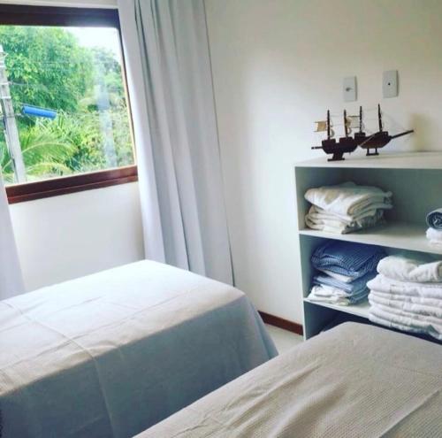 a bedroom with a bed and a window with towels at Barra Grande Pe na Areia Beira Mar in Barra Grande