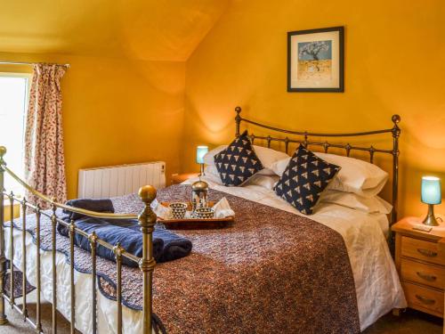 a bedroom with a bed with yellow walls at Fox Cottage in Henstead