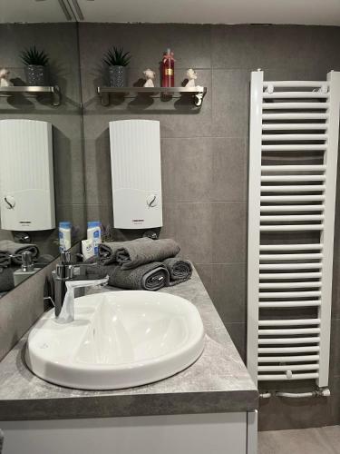 La salle de bains est pourvue d'un lavabo blanc et d'un miroir. dans l'établissement Airport Gate 25, à Ledine