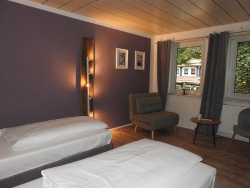 a bedroom with two beds and a chair and a window at Haus Hohensee in Clausthal-Zellerfeld