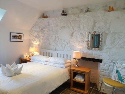 a bedroom with a white bed and a stone wall at Harbour view in Tobermory