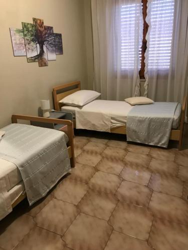 Zimmer mit 3 Betten und einem Fenster in der Unterkunft Appartamento luminoso e spazioso al primo piano in Capoterra