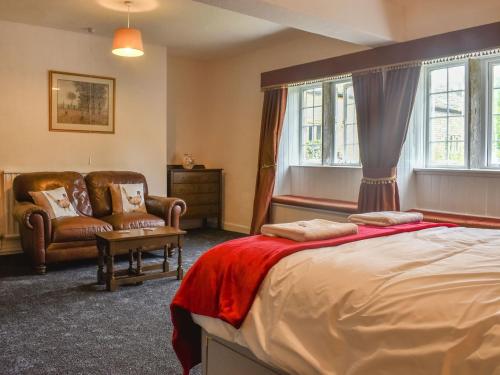 a bedroom with a bed and two chairs and windows at Foxstones Farm House in Worsthorne