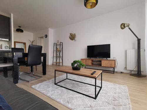 een woonkamer met een bank, een tafel en een televisie bij Cosy'part Gold. in Bezons