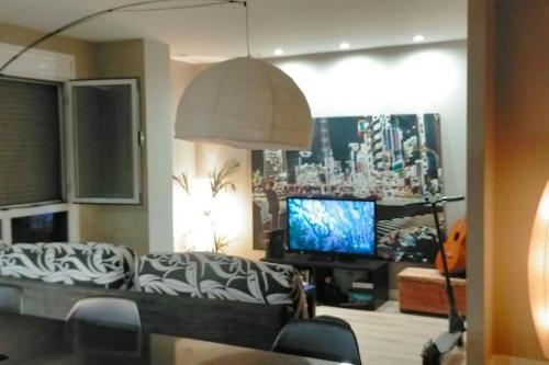 uma sala de estar com um sofá e uma televisão em luminoso duplex en Las Canteras (Surf Zone) em Las Palmas de Gran Canaria